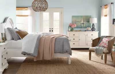 pale blue coastal bedroom with rattan light fixture and sisal rug and farmhouse furniture